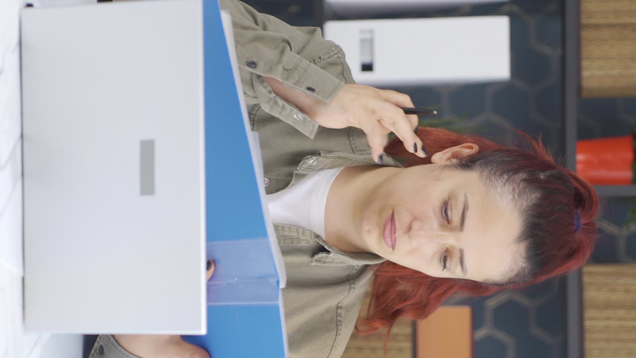 video vertical de una mujer de negocios trabajando mirando archivos de papeleo.