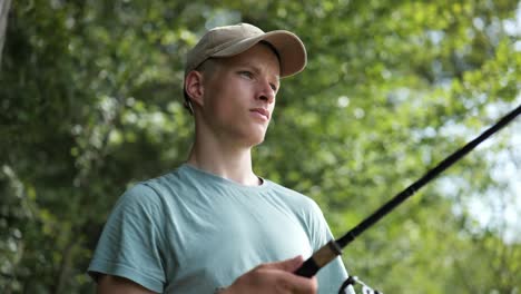 male angler gets fishing rod out surrounded by trees on sunny day, close-up