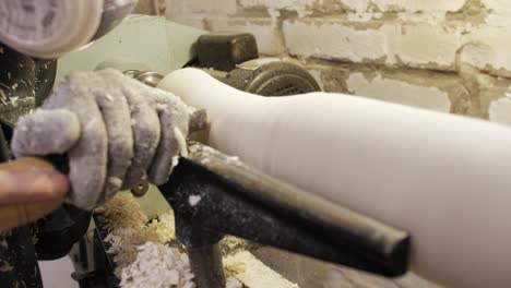 woodworker planing a table leg with wood chips flying