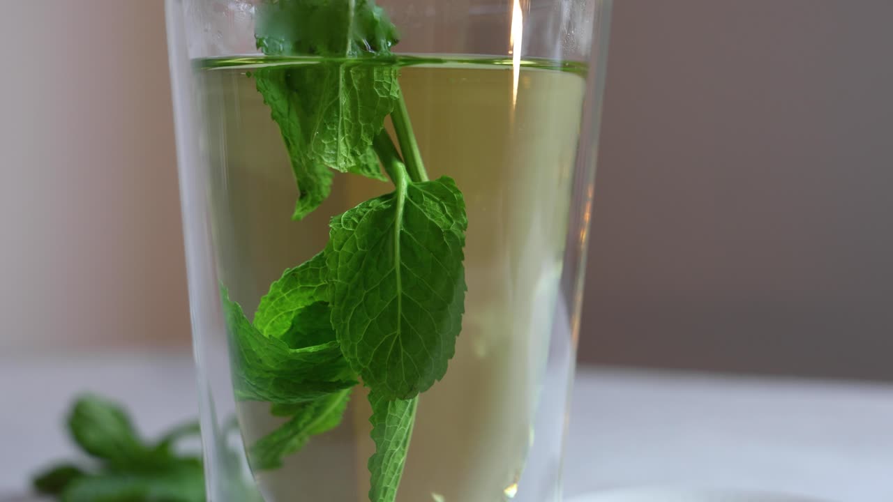 Primo piano di foglie di menta aggiunte ad acqua calda per il tè.