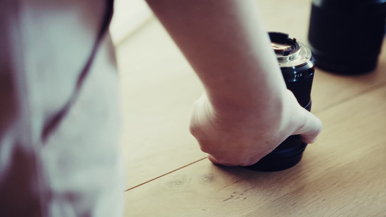 한 여성이 렌즈를 가져와 카메라에 부착합니다. 카메라 움직임과 함께 낮의 스튜디오 설정입니다.