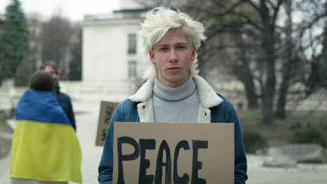 young caucasian man standing with manifest banner on cardboard.