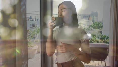 animation of light spots over biracial woman holding mug and drinking