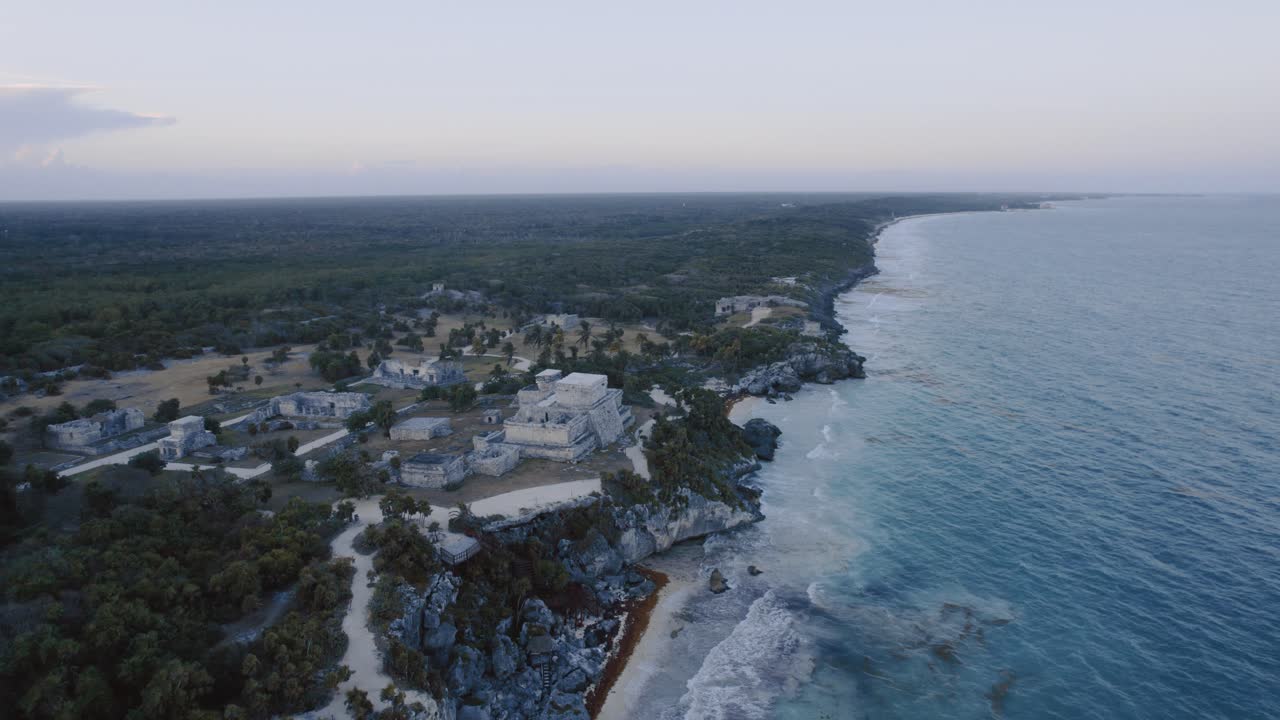 erial dolly drone tiro de la costa en tulum méxico con rocas, playa de arena y las ruinas mayas con vista al cielo nublado 4k