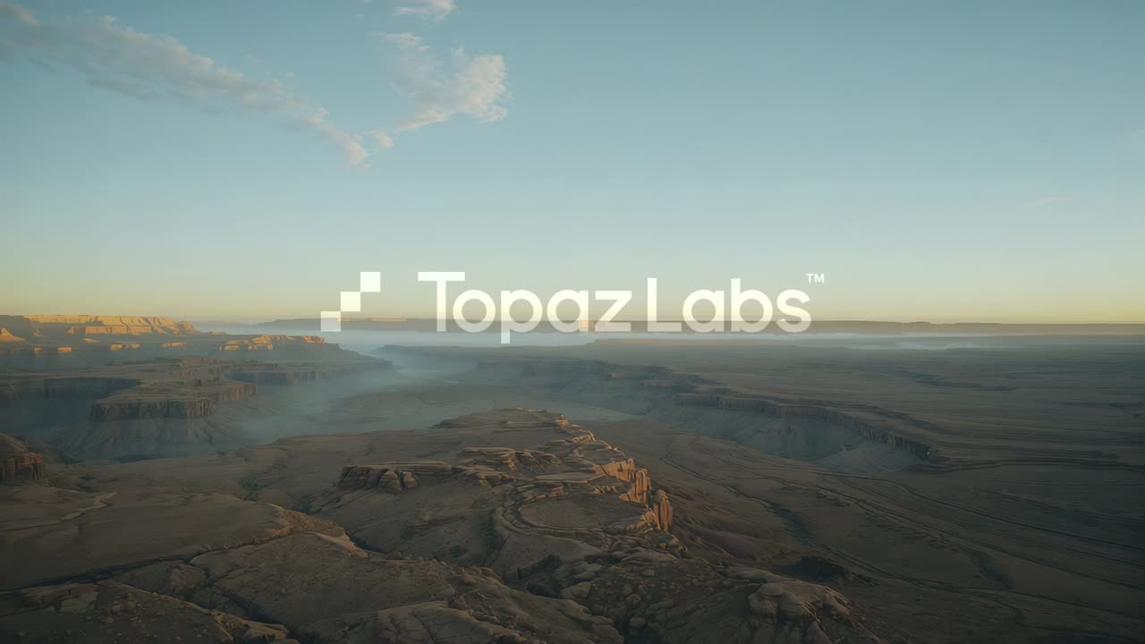 Gliding drone camera revealing aerial desert canyon landscape over mesa, with Topaz Labs logo