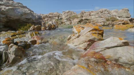 closeup of ocean water running through rock formations of hangklip bay