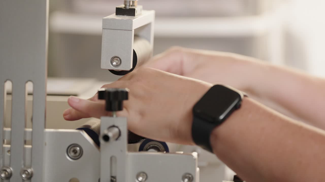 Close-up of an industrial labeling machine applying a label to a brown glass bottle in a pharmaceutical or cosmetic production facility. (4K)