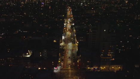 High-angle-view-of-night-city.-Forwards-fly-above-vehicles-driving-on-multilane-straight-street-glowing-into-darkness.-Manhattan,-New-York-City,-USA