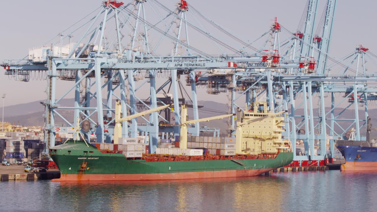 Large cargo ship docked at a port with gantry cranes