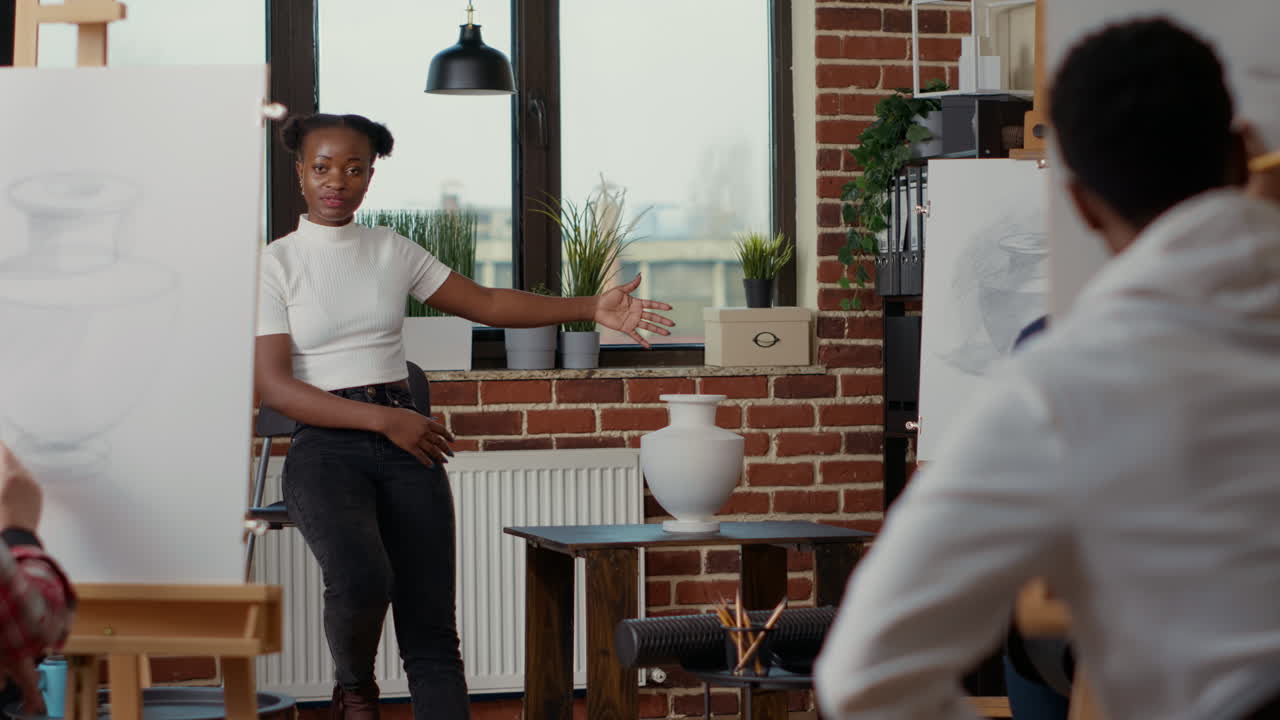 Young artist pointing at vase model on table to teach drawing practice