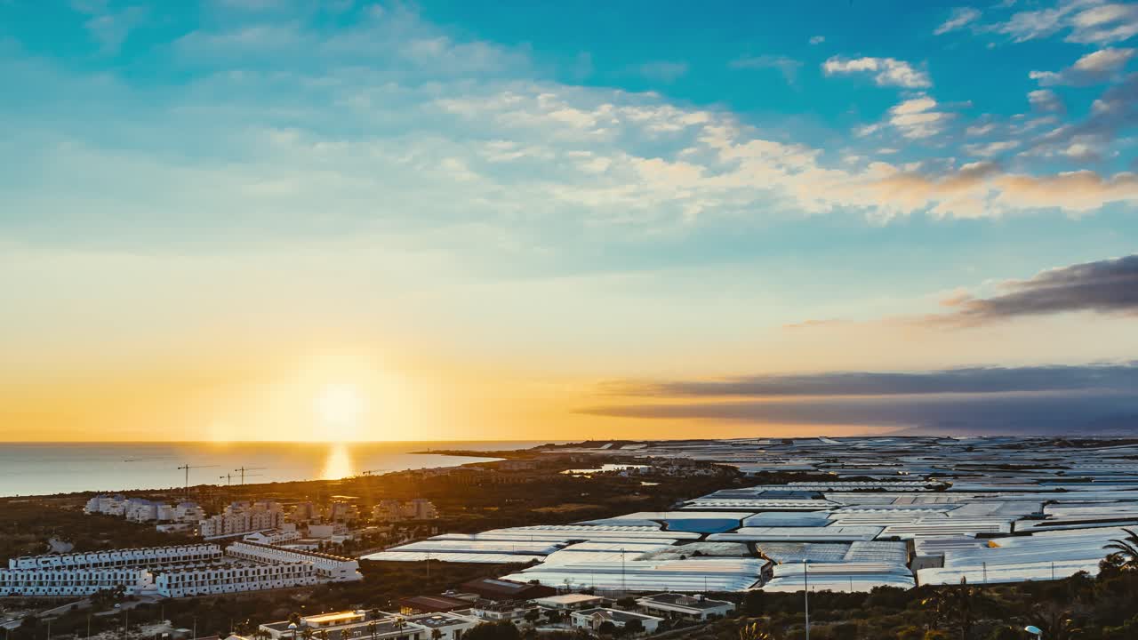 Sunset Over Coastal City and Greenhouses
