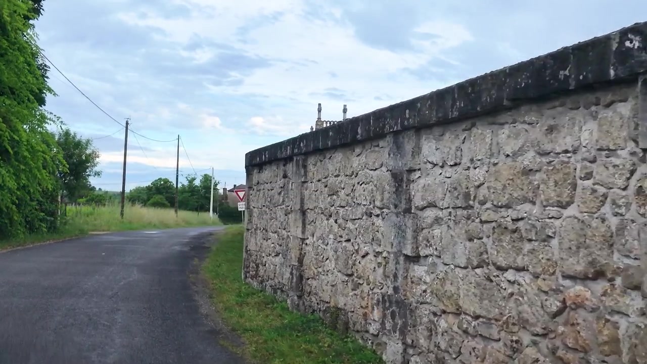 Antigo muro de pedra e estrada rural levando a uma igreja de vila