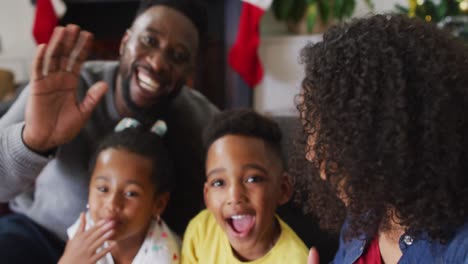 smiling african american family sending kisses on video call, christmas decorations in background