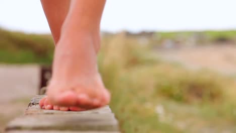 Girl-walking-across-a-wooden-fence-by-the-beach