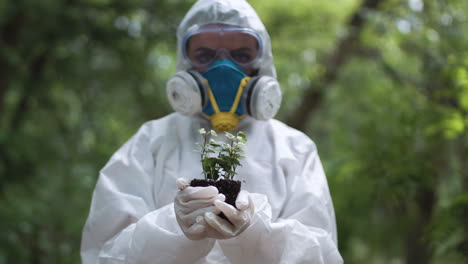 scientist in hazmat suit holding plant