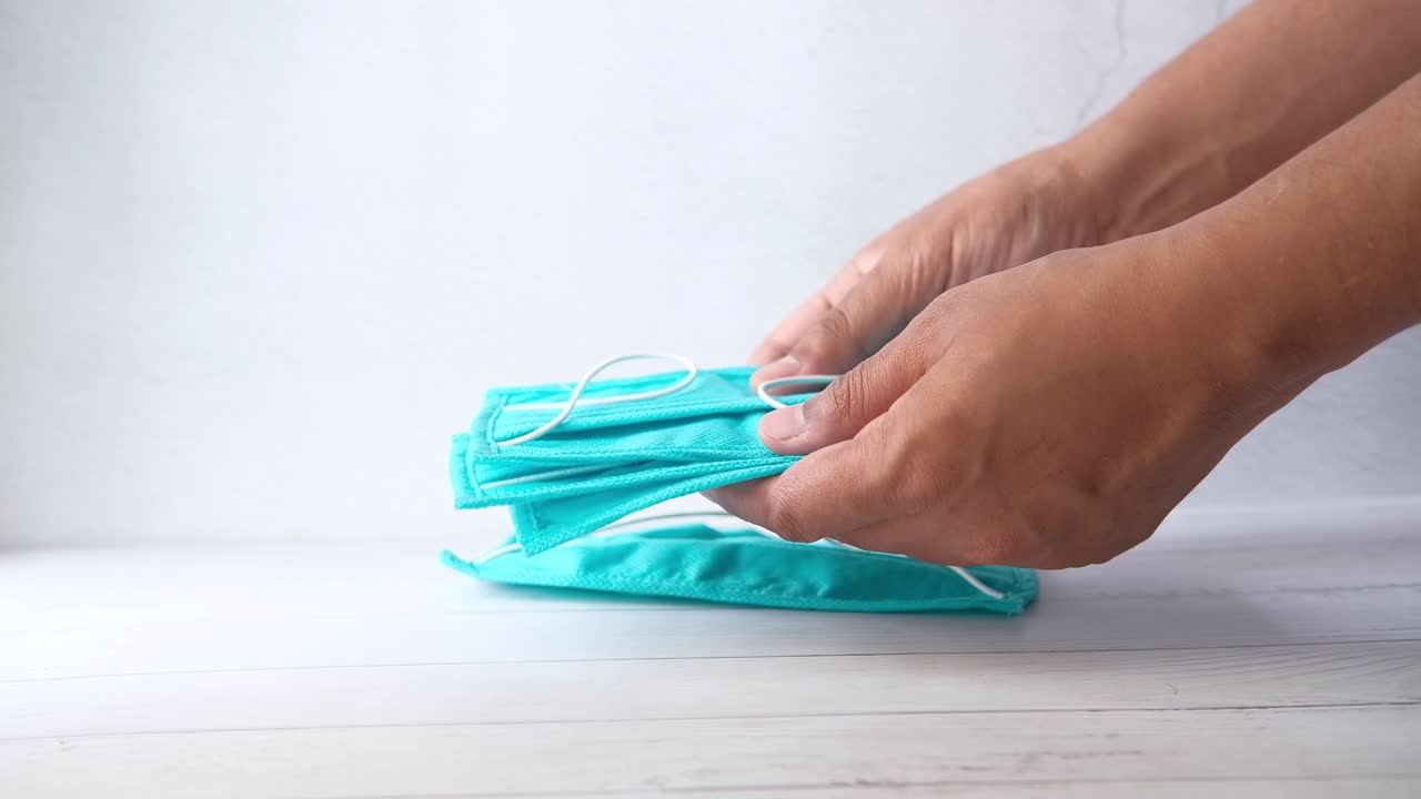 manos sosteniendo una pila de máscaras faciales azules claras