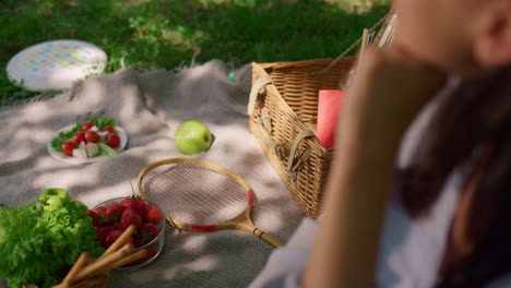 woman sitting on picnic blanket with diverse snacks blurred view close up.