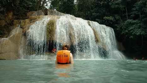 person swimming in waterfall in jungle