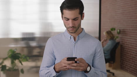 portrait-of-young-handsome-middle-eastern-businessman-texting-browsing-using-smartphone-mobile-technology-checking-messages-in-office-workspace