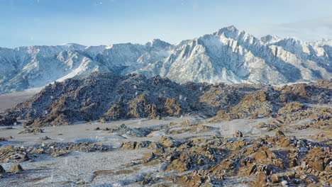 rocky desert area and mountain range during snowfall, aerial drone view