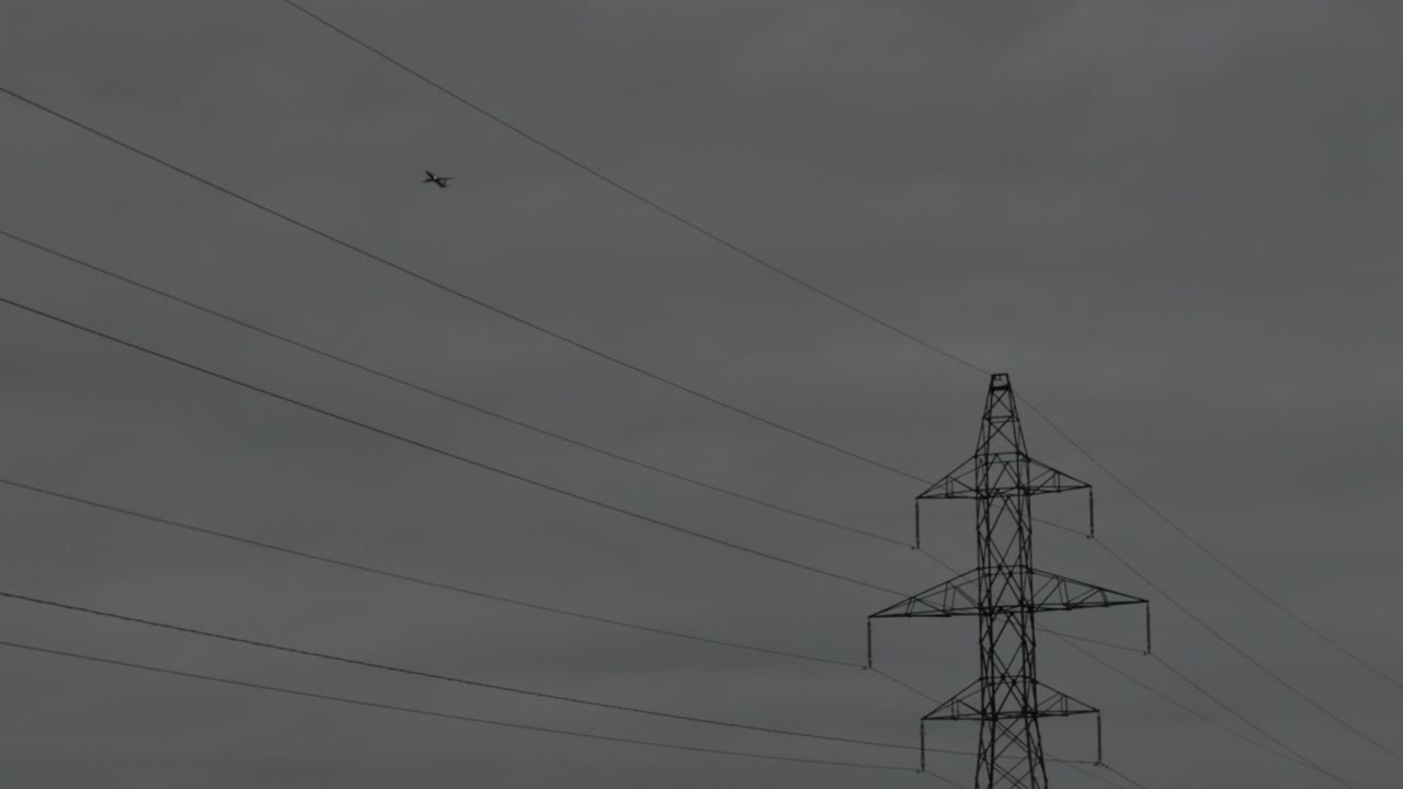 самолет пролетает над опорой лэп