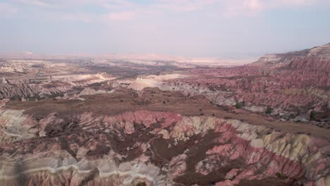 Aerial-drone-pan-shot-over-Red-Valley-with-it's-spectacular-volcanic-shaped-rocks,-located-in-Cappadocia,-Turkey-on-a-cloudy-day