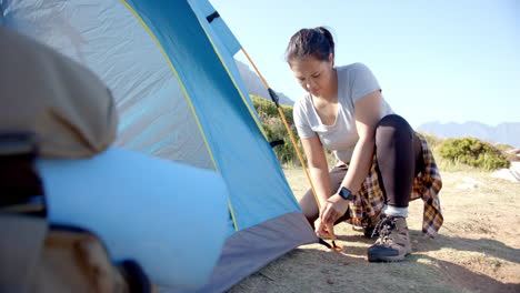 setting up tent, woman preparing campsite during mountain hike in nature