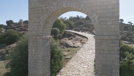 drone flies through stone archway entrance to historical spanish holy basilica landmark