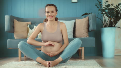 happy future mother looking on camera indoors. expectant mother holding belly