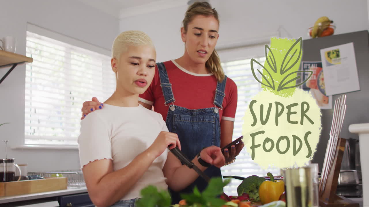 Animation of super foods text over diverse female couple cooking at home