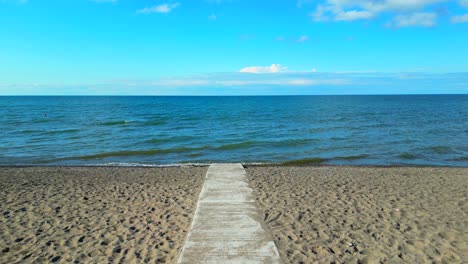 vuelo aéreo sobre un camino de hormigón hasta la orilla del agua - playa accesible para sillas de ruedas