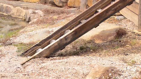 water flows through a wooden chute into a pond