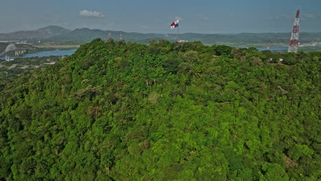 ciudad de panamá aérea v64 cinemática dolly en el paso elevado ancon hill capturando la bandera nacional ondulada, revela el canal de agua, el puerto de balboa y el puerto del astillero comercial - filmado con el cine mavic 3 - marzo de 2022