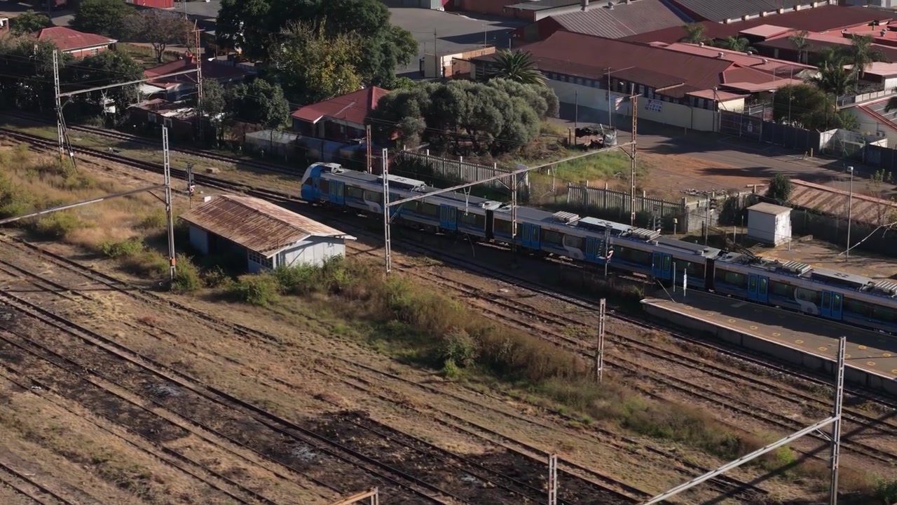 Aerial view of a passenger train travelling along railway tracks through a densely built industrial area