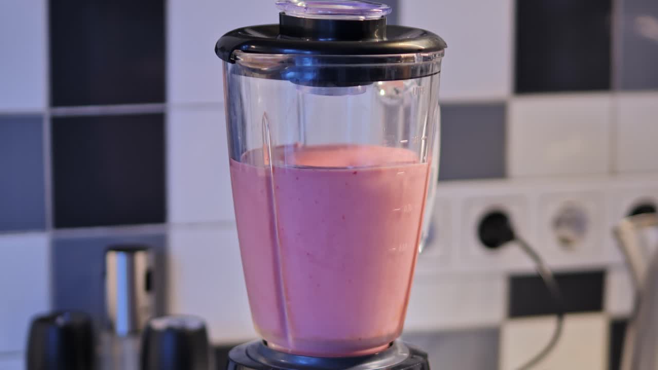 Twilight kitchen scene with blender making fresh strawberry-banana smoothie - 4K