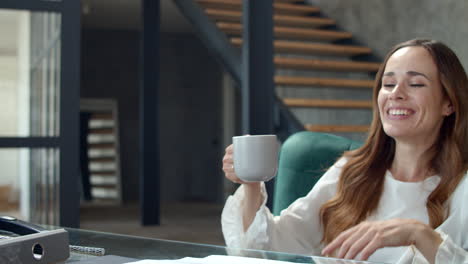 portrait of happy woman feeling satisfied on workplace. lady drinking tea.