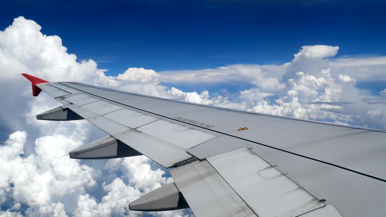 4k imágenes vuelo de avión. ala de un avión volando por encima de las nubes blancas y el cielo azul. hermosa vista aérea desde la ventana del avión en el tiempo de viaje en avión. vacaciones, tiempo de vacaciones
