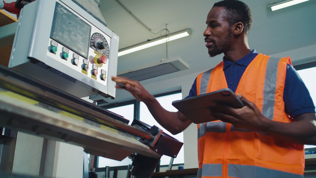 Portrait of a smiling african american worker in a safety orange vest using a digital tablet in a