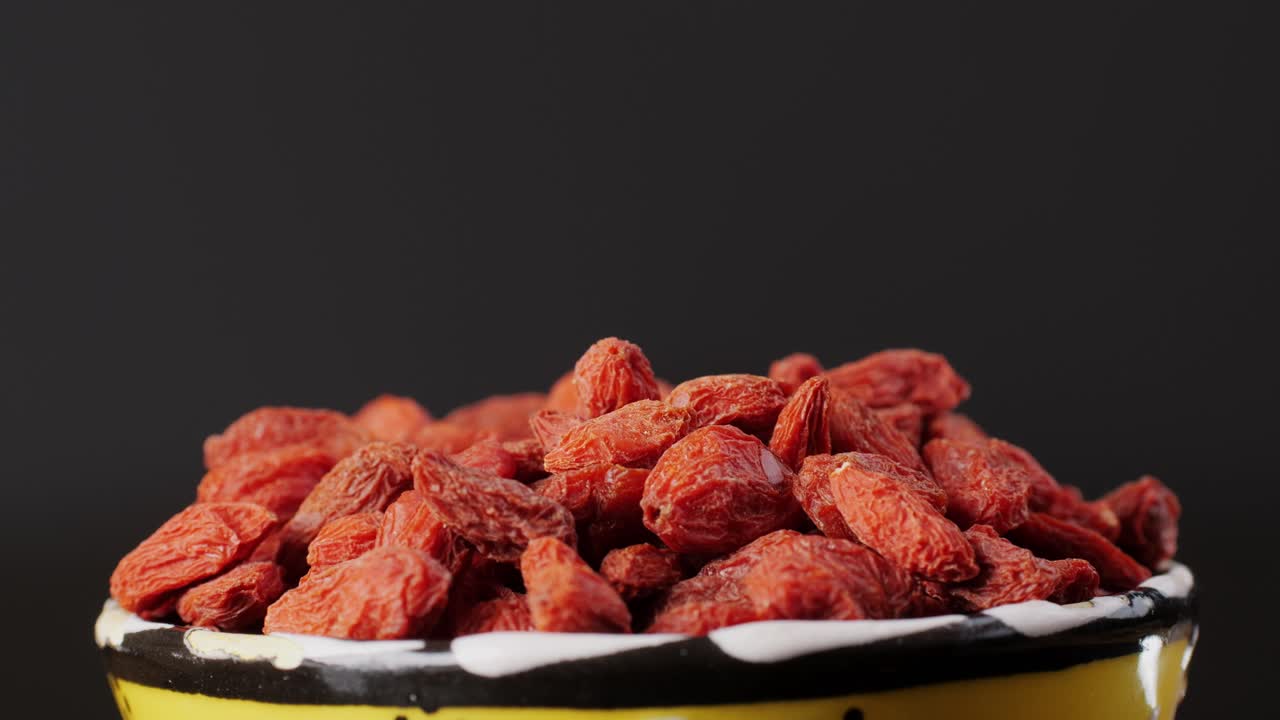 Hand picking Goji Berries from a Bowl
