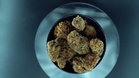 un movimiento de grúa cinematográfico de arriba hacia abajo detallado de una planta de cannabis, cepas híbridas de naranja, tipo indica, flor de marihuana, cámara lenta 120 fps, luces de estudio, soporte giratorio brillante