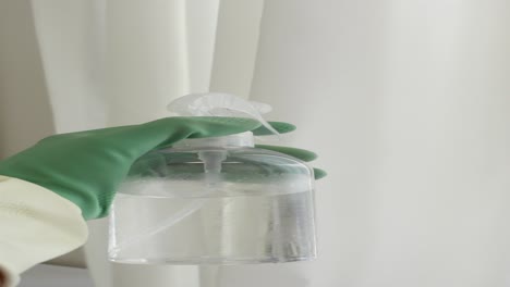 close-up of a gloved hand holding a spray bottle