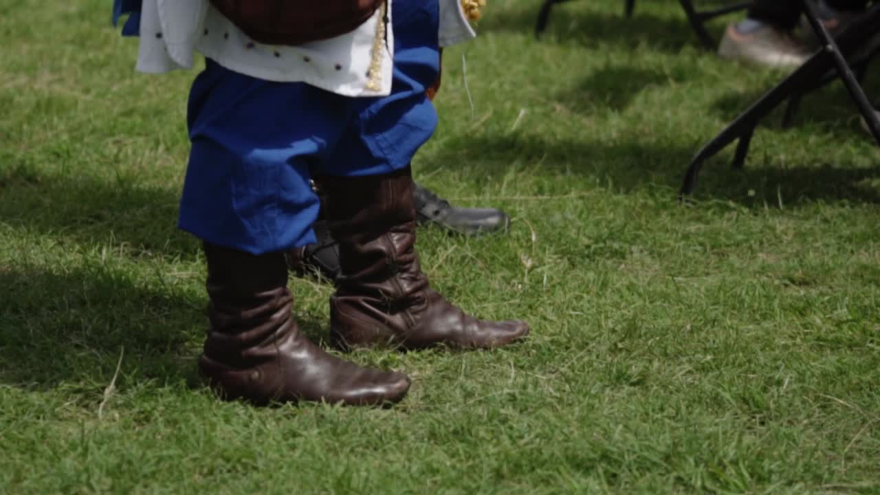 Medieval knight adjusting armor before combat during a reenactment, preparing for battle in a field