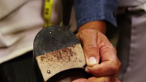zapatero martillando el clavo en un zapato