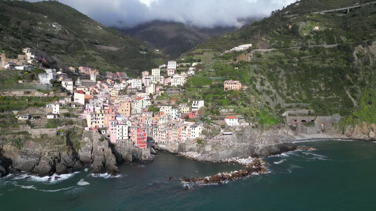 Riomaggiore Cinque Terre Italy aerial high and wide shows clouds in the mountains above the village