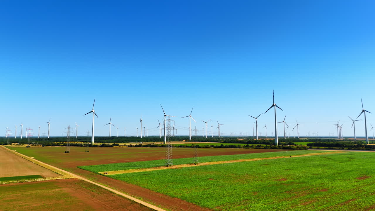 Footage over the field along the electricity power lines and wind farms. Green energy concept