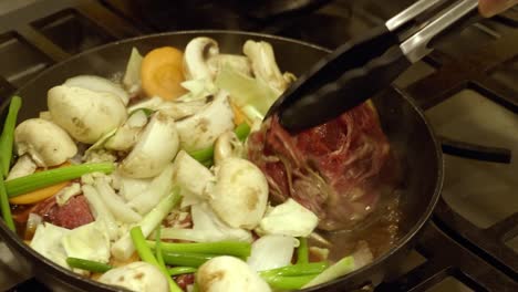 cooking korean dish in a pan using kitchen tong