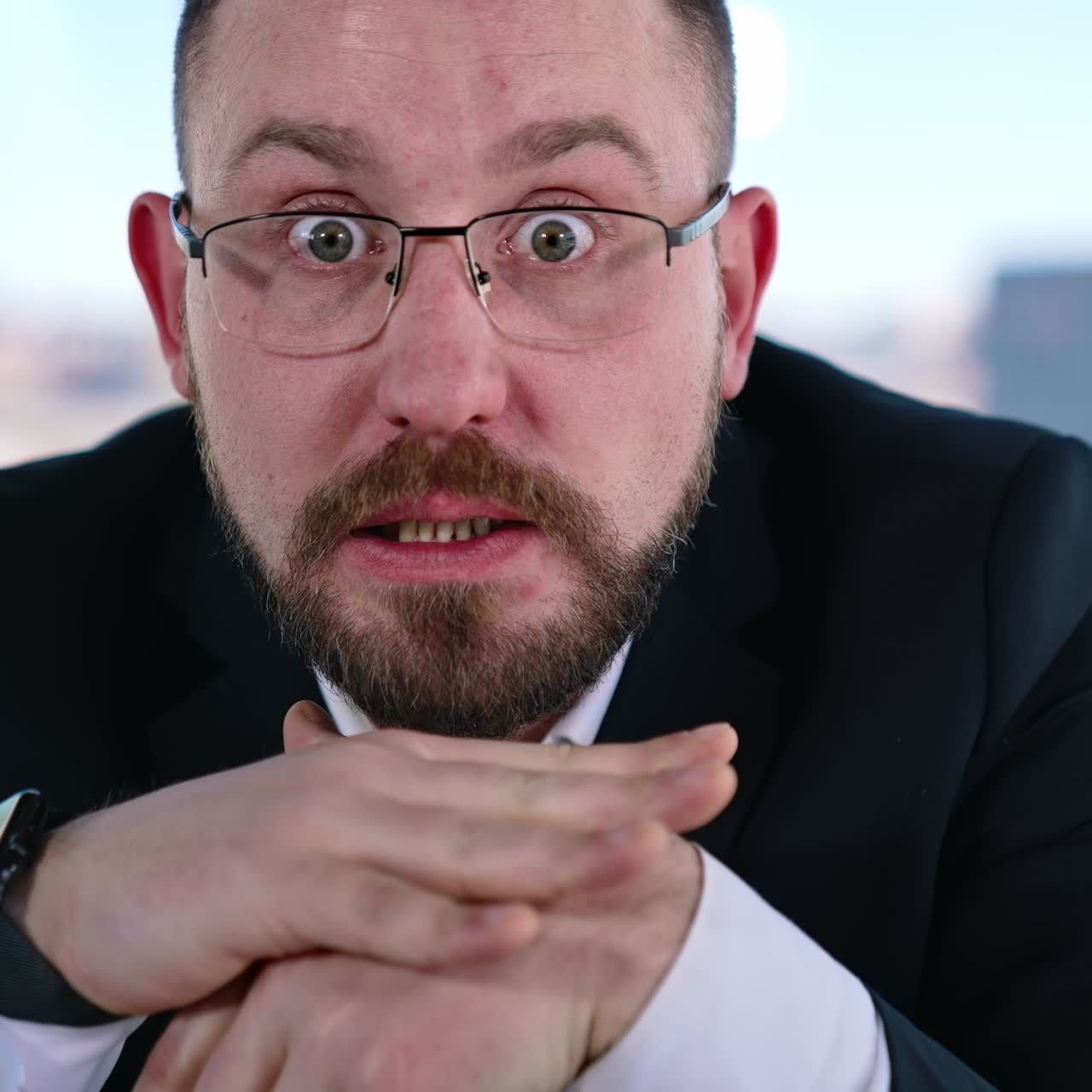 Depressed businessman sits at desk. Bearded middle aged man in glasses with his hands on head sitting at workplace and thinks. Portrait of sad businessman in office