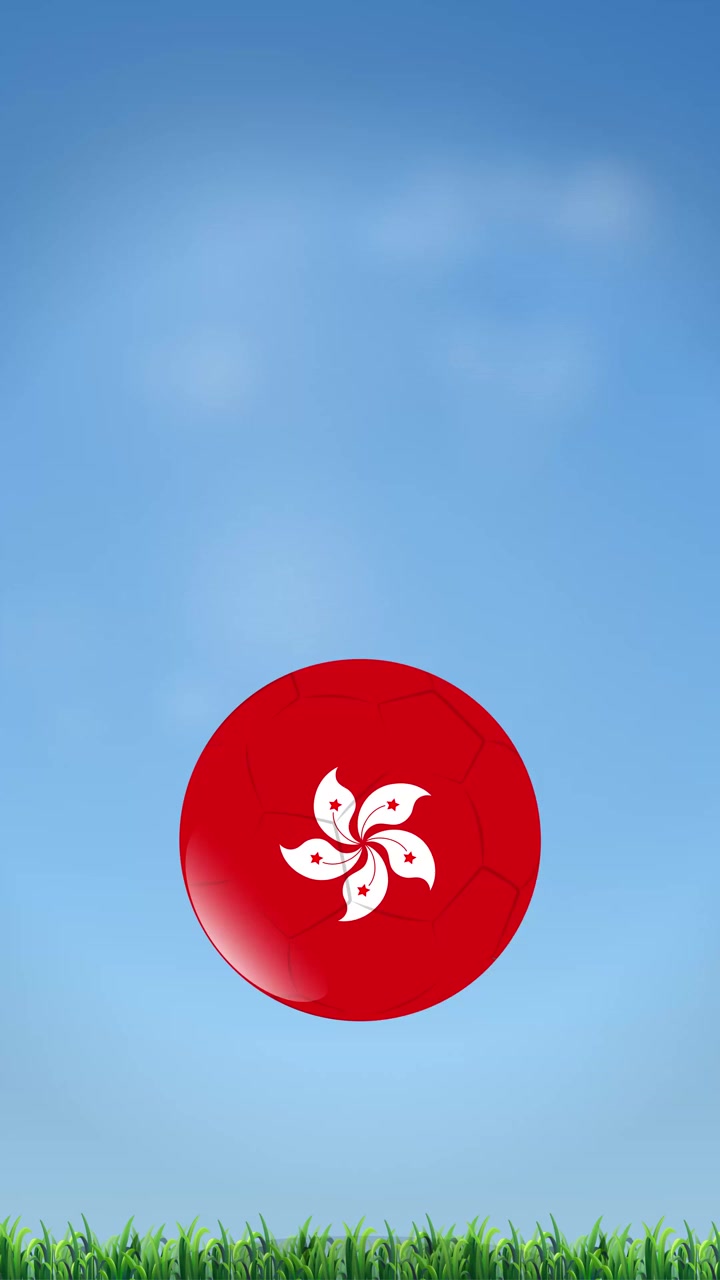 Bola sepak merah dengan lambang bunga putih memantul di atas rumput hijau dan langit.