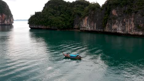 imágenes de drones de un bote de cola larga navegando alrededor de las islas de tailandia con las formaciones rocosas de piedra caliza que sobresalen del agua y el océano en el fondo-7