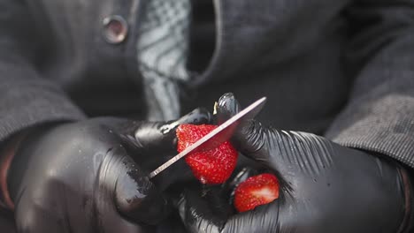 person cutting strawberries with gloves